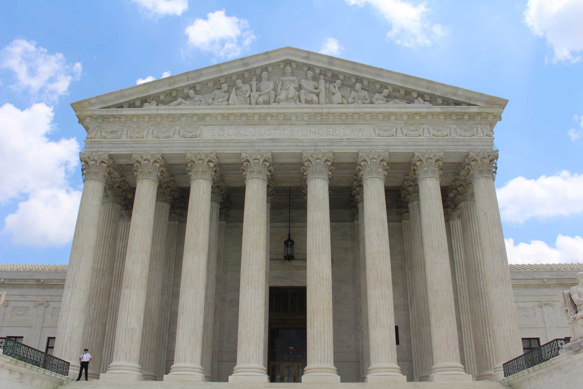 entrance of large courthouse with blue cloudy sky in the background