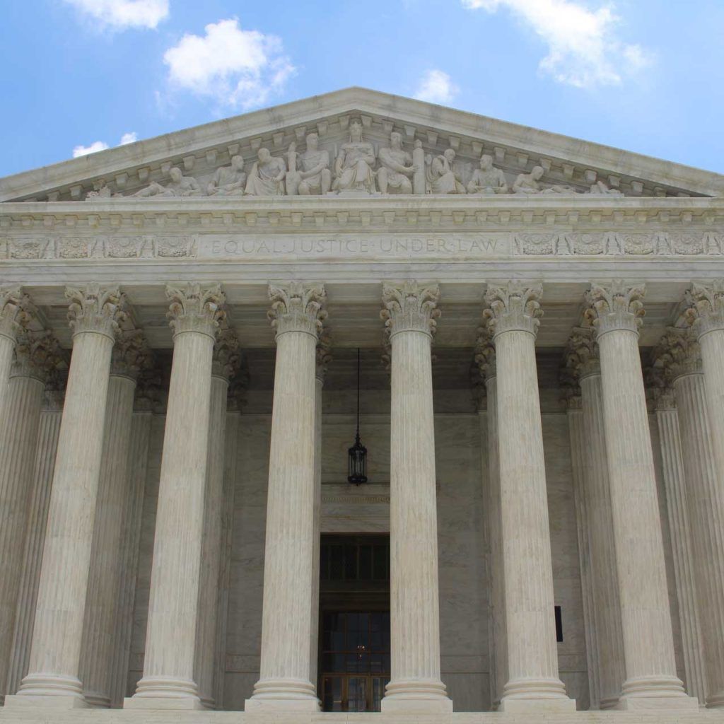 entrance of large courthouse with blue cloudy sky in the background